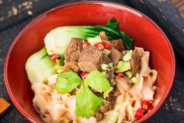 Spicy red soup beef noodle in a bowl on wooden table