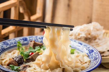 Spicy red soup beef noodle in a bowl on wooden table