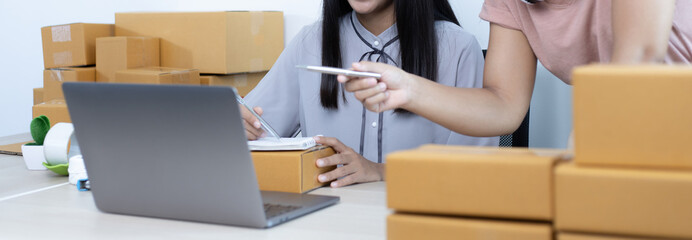 Two young Asian women chat with bright smiles to customers who shop online via laptop and confirm the order to close the deal, Selling products online or doing freelance work at home concept.