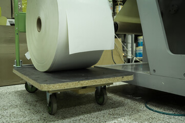 A roller of white printing paper on a trolley in a printing house. Paper for printing self-adhesive...