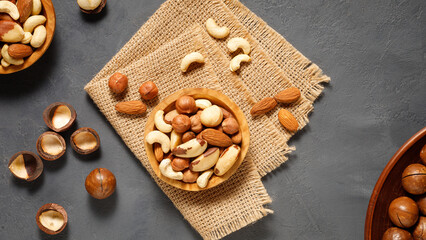 Various nuts in bowl - cashew, hazelnuts, almonds, brazilian nuts and macadamia on a gray stone background. Top view.