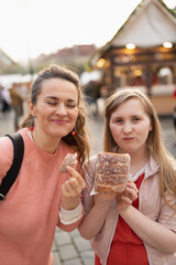 smiling modern mother and child at fair in city eating trdelnik