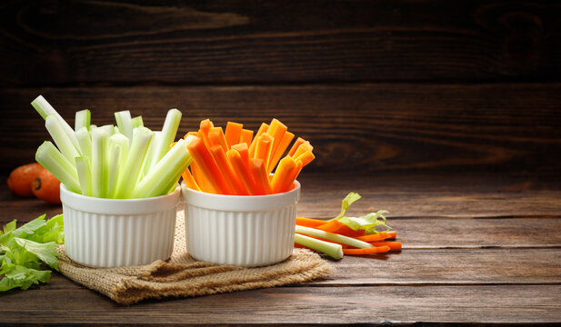 Fresh vegetables - chopped celery sticks and carrots on a wooden background. Diet and healthy food. Copy space for text.