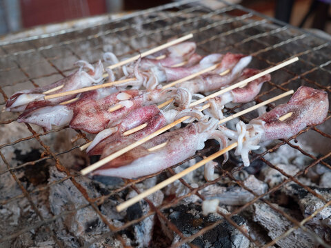  street food. Grilled squid on a charcoal grill sold in a street stall.