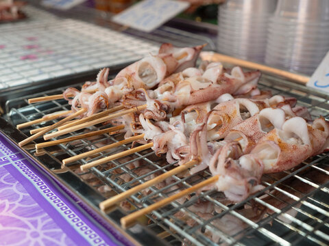  street food. Grilled squid on a charcoal grill sold in a street stall.
