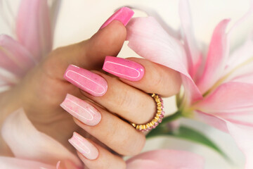 Pink elongated nail extension with fine glitter.