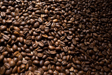 Roasted coffee beans texture. Top view, flat lay. Place for text. Copy space. Rays of the sun shine on the coffee beans.