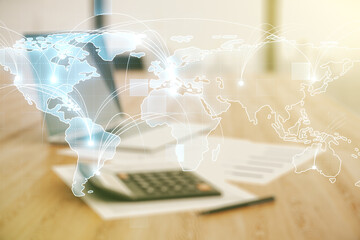 Abstract graphic digital world map hologram with connections on blurry calculator and computer...