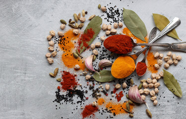 Vintage silver spoons with aromatic Indian spices. Colorful still life with paprika, turmeric,...