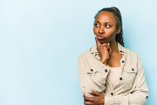 Young african american woman isolated on blue background looking sideways with doubtful and skeptical expression.