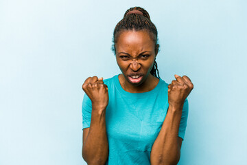 Young african american woman isolated on blue background showing fist to camera, aggressive facial...