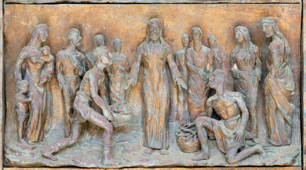 MONOPOLI, ITALY - MARCH 6, 2022: The bronze relief  the Miracle of Multiplication on the gate of church Chiesa di Sacro Cuore by Wolfgang Stempfele from year 2002.