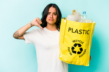 Young hispanic woman recycling plastic isolated on yellow background showing a dislike gesture, thumbs down. Disagreement concept.