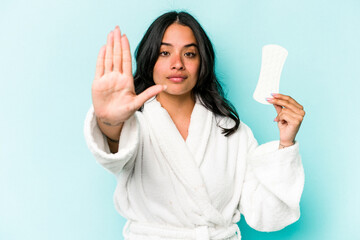 Young caucasian woman holding sanitary napkin isolated on pink background standing with...