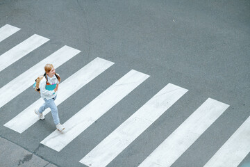 pupil crossing crosswalk and going to school outdoors in city - obrazy, fototapety, plakaty