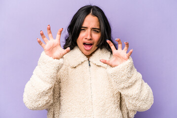 Young hispanic woman isolated on purple background upset screaming with tense hands.