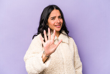 Young hispanic woman isolated on purple background being shocked due to an imminent danger