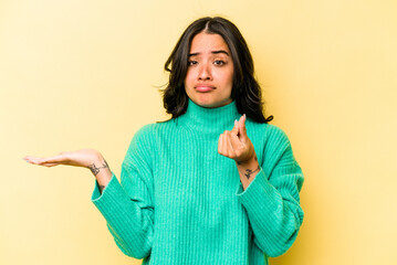 Young hispanic woman isolated on yellow background showing that she has no money.