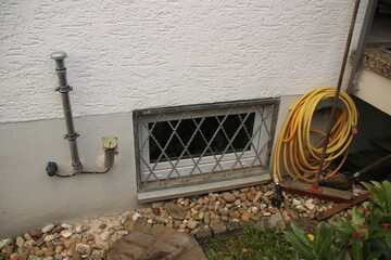 Hauswand mit vergittertem Fenster Schlauch und Öffnung für Heizöl