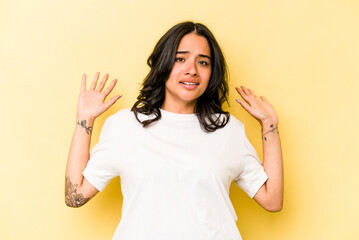 Young hispanic woman isolated on yellow background being shocked due to an imminent danger