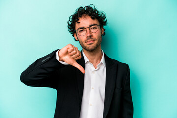 Young caucasian business man isolated on blue background showing a dislike gesture, thumbs down....