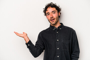 Young caucasian man isolated on white background impressed holding copy space on palm.