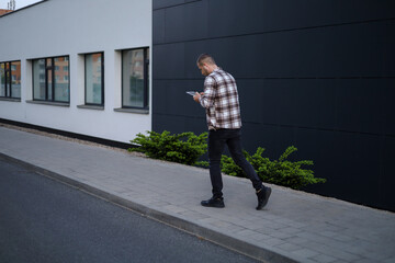 A man works with a tablet in the park near office buildings