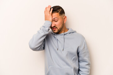Young hispanic man isolated on white background forgetting something, slapping forehead with palm...