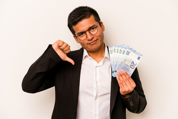 Young hispanic business man holding banknotes isolated on white background feels proud and self...