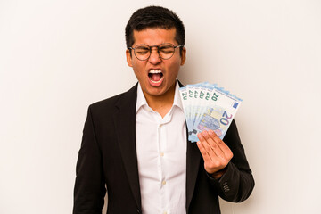 Young hispanic business man holding banknotes isolated on white background screaming very angry and aggressive.