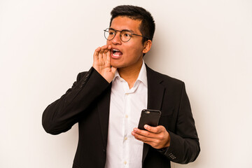 Young business hispanic man holding mobile phone isolated on white background shouting and holding palm near opened mouth.