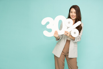 Portrait of Asian business woman standing and holding 30% number or thirty percent isolated on green background - obrazy, fototapety, plakaty