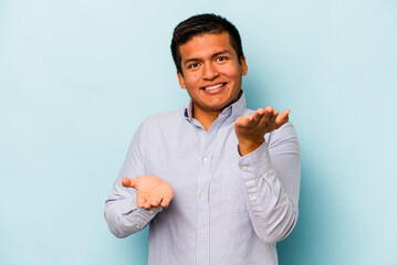 Young hispanic man isolated on blue background makes scale with arms, feels happy and confident.