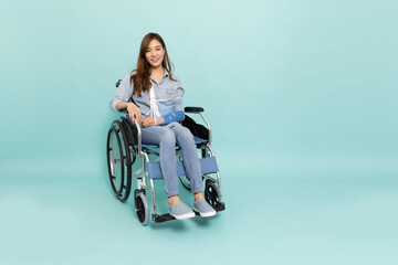 Young Asian woman sitting on wheelchair and put on a soft splint due to a broken arm isolated on...