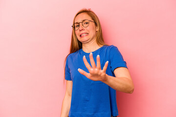 Young caucasian woman isolated on pink background being shocked due to an imminent danger
