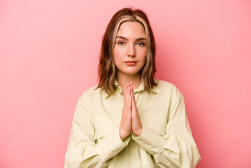 Young caucasian woman isolated on pink background praying, showing devotion, religious person...