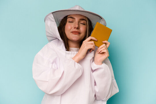 Young caucasian beekeeper woman isolated on blue background