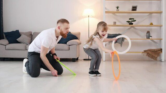 Man showing jugglery by using colorful cirlces. Father with his little daughter is at home indoors