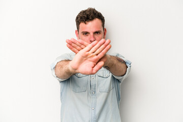Young caucasian man isolated on white background doing a denial gesture