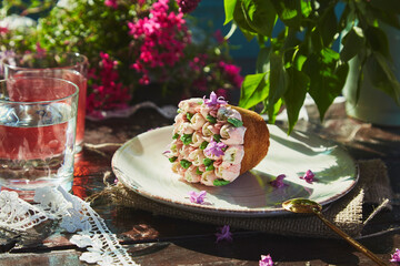 Aesthetic outdoor picnic with water and compote, beautiful cupcake with handmade flowers, flowers and lace decoration. Rural picnic with bright spring, summer tones of flowers on a sunny day.