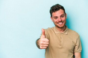 Young caucasian man isolated on blue background smiling and raising thumb up