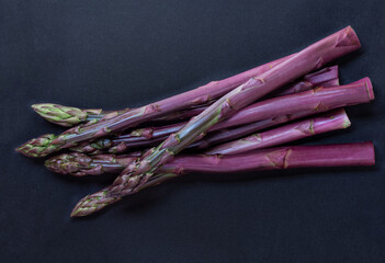 Asparagus. Fresh purple asparagus on black slate background. Top view copy space.
