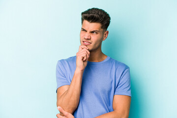 Young caucasian man isolated on blue background suffers pain in throat due a virus or infection.