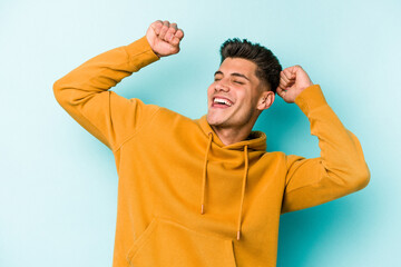 Young caucasian man isolated on blue background celebrating a special day, jumps and raise arms with energy.