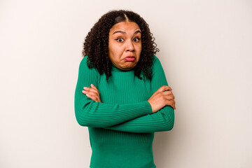 Young African American woman isolated on white background shrugs shoulders and open eyes confused.