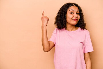 Young African American woman isolated on beige background showing number one with finger.