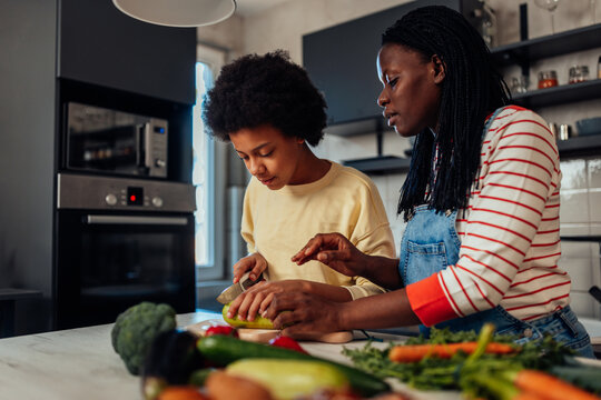 Mom And Daughter Cooking In Kitchen