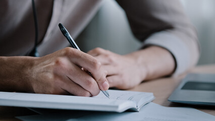 Close up unknown right-handed male business man write notes business ideas at organizer writer sit...