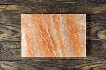 Pink himalayan salt block for cooking and serving the dish on oak wooden table with copy space - obrazy, fototapety, plakaty