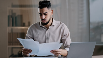 Frustrated hispanic young guy business man in office sadness accountant stressed about bank loan payments mistake in financial report document cross fingers pray say prayer hopes for good luck wishes